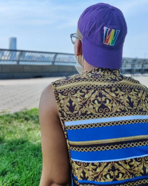 Backside photo of Moiz sitting on lawn with Williams pride hat