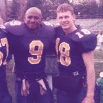 Two male students pose together in their football uniforms.