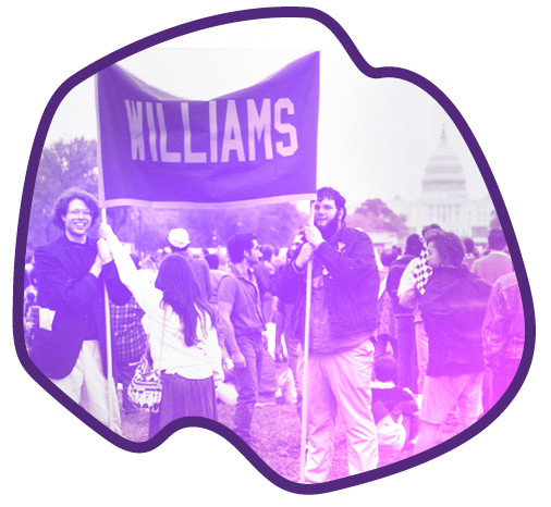 two persons holding a Williams banner with many people in the background