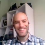 of man sitting down and smiling.