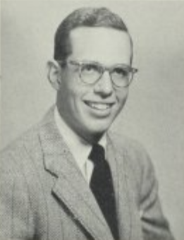 Black and White headshot of a man in glasses and a suit and tie