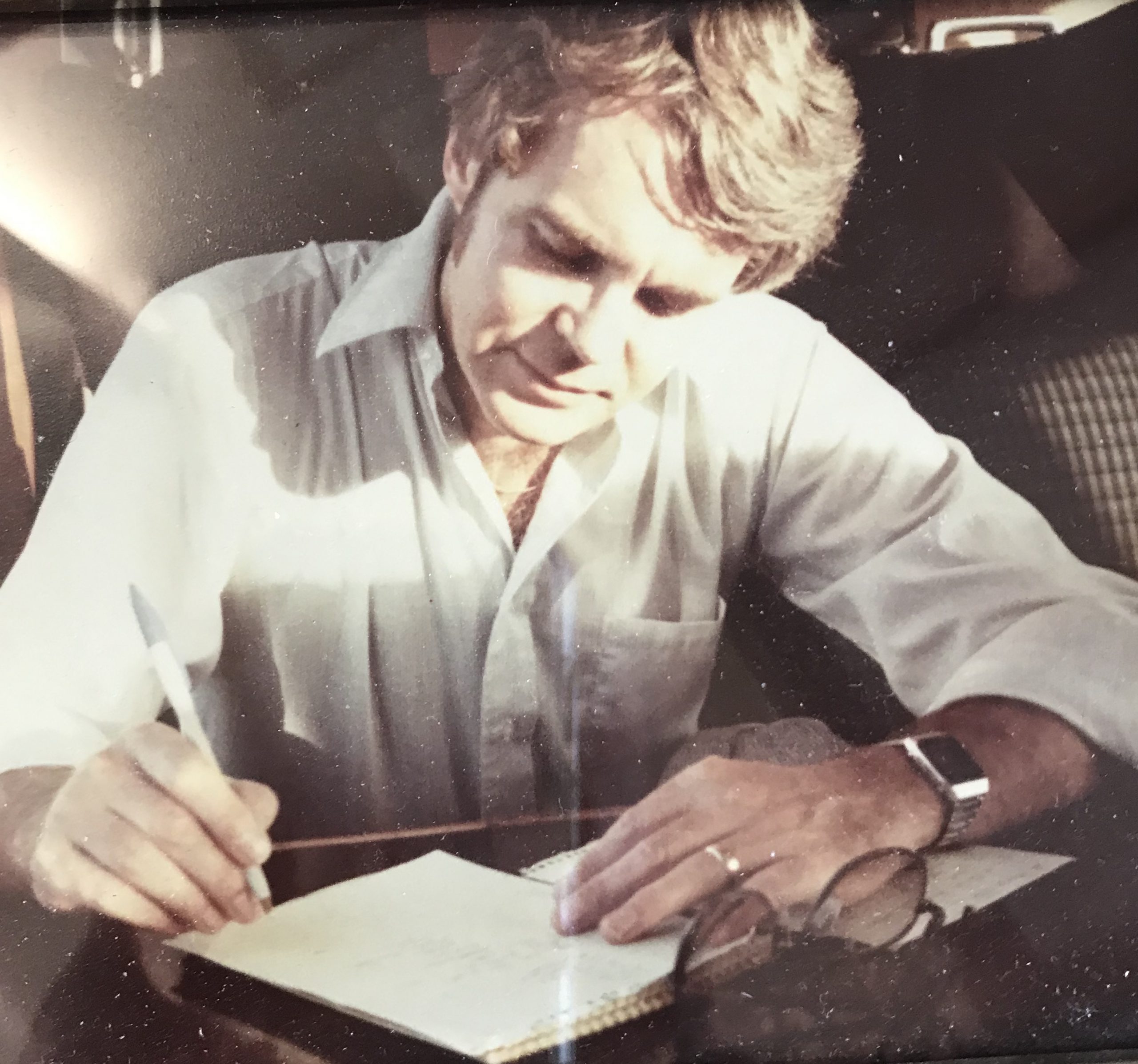 Man leaning over writing page with pen in hand