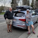 Two people standing in front of a car with Prpcow license plate