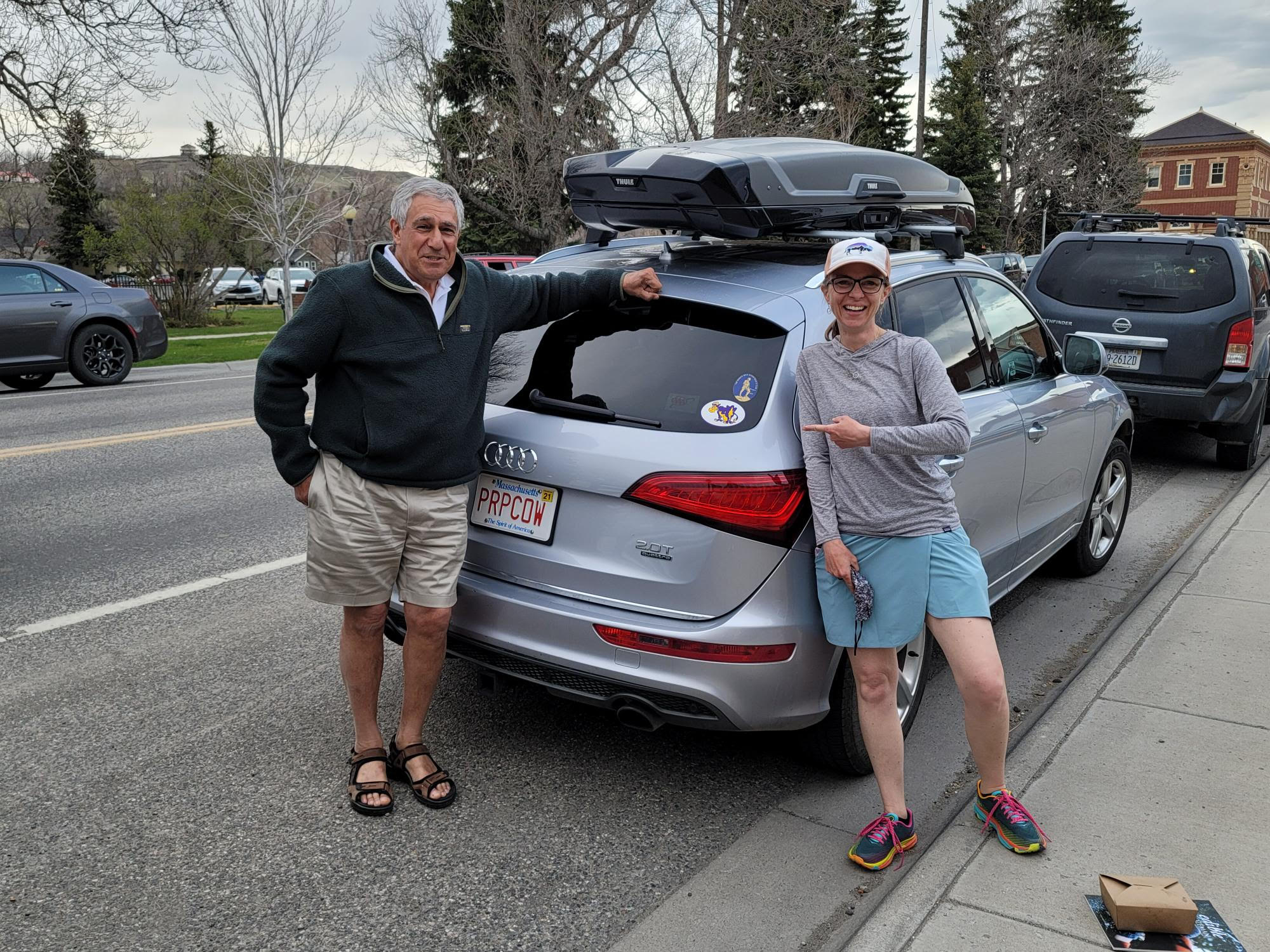 Two people standing in front of a car with Prpcow license plate