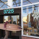 Man holding surfboard outside shop