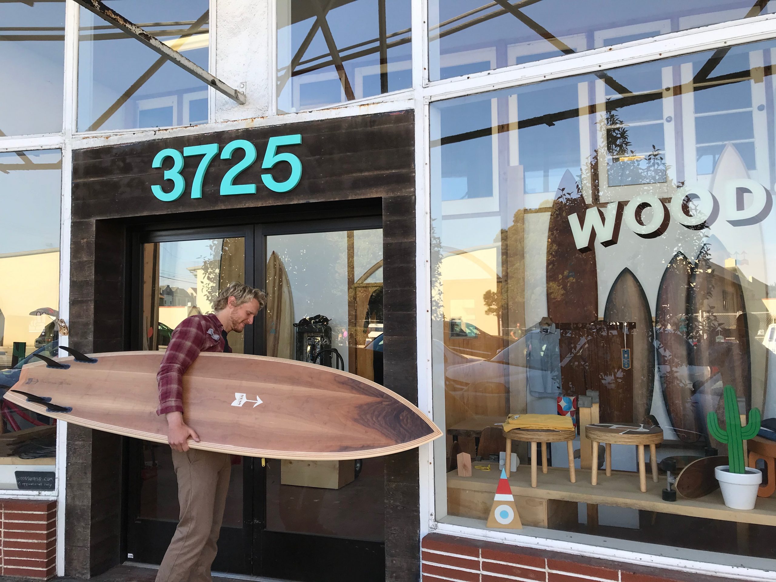 Man holding surfboard outside shop