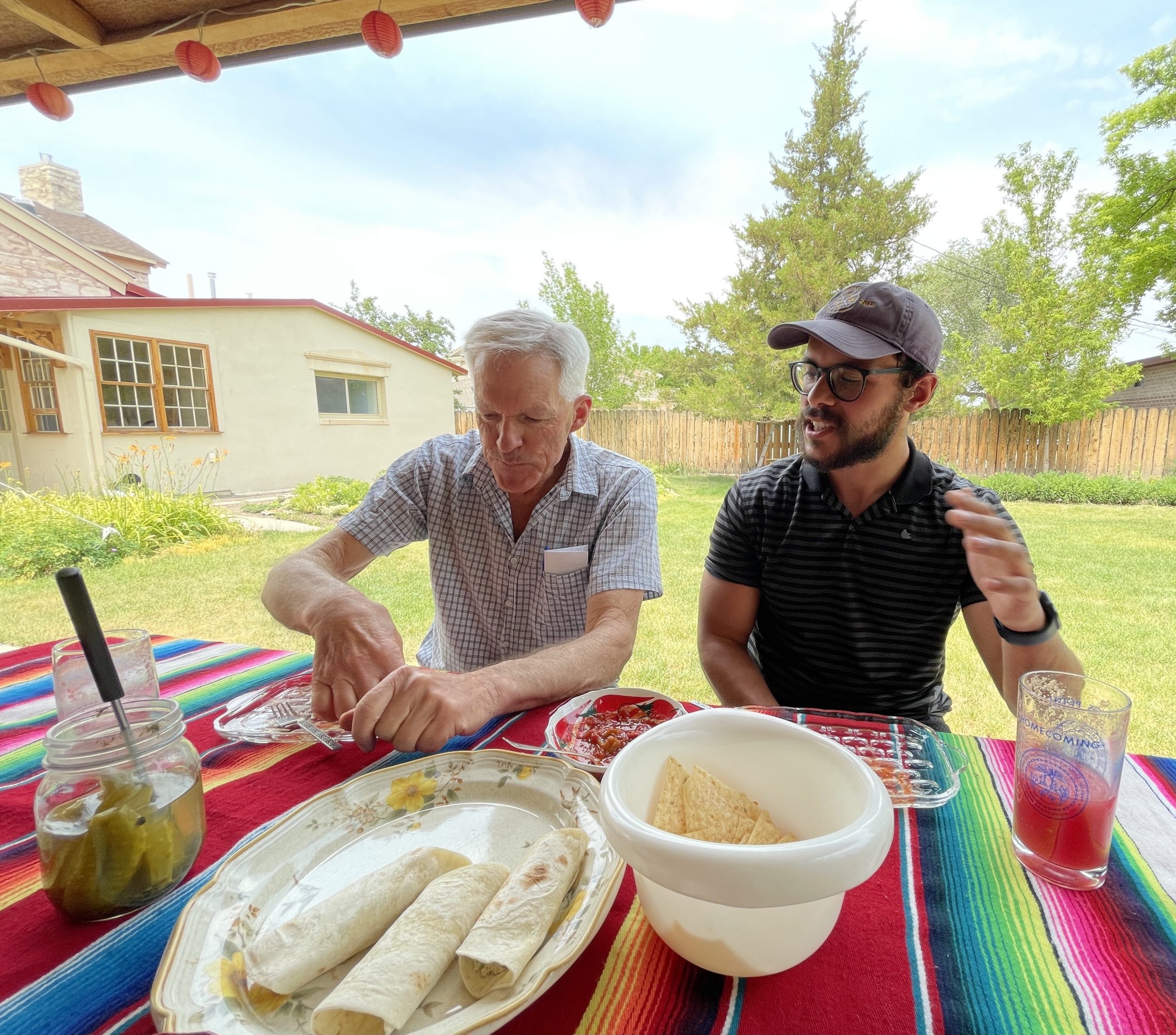 2 people in conversation during lunch at a picnic table outdoors
