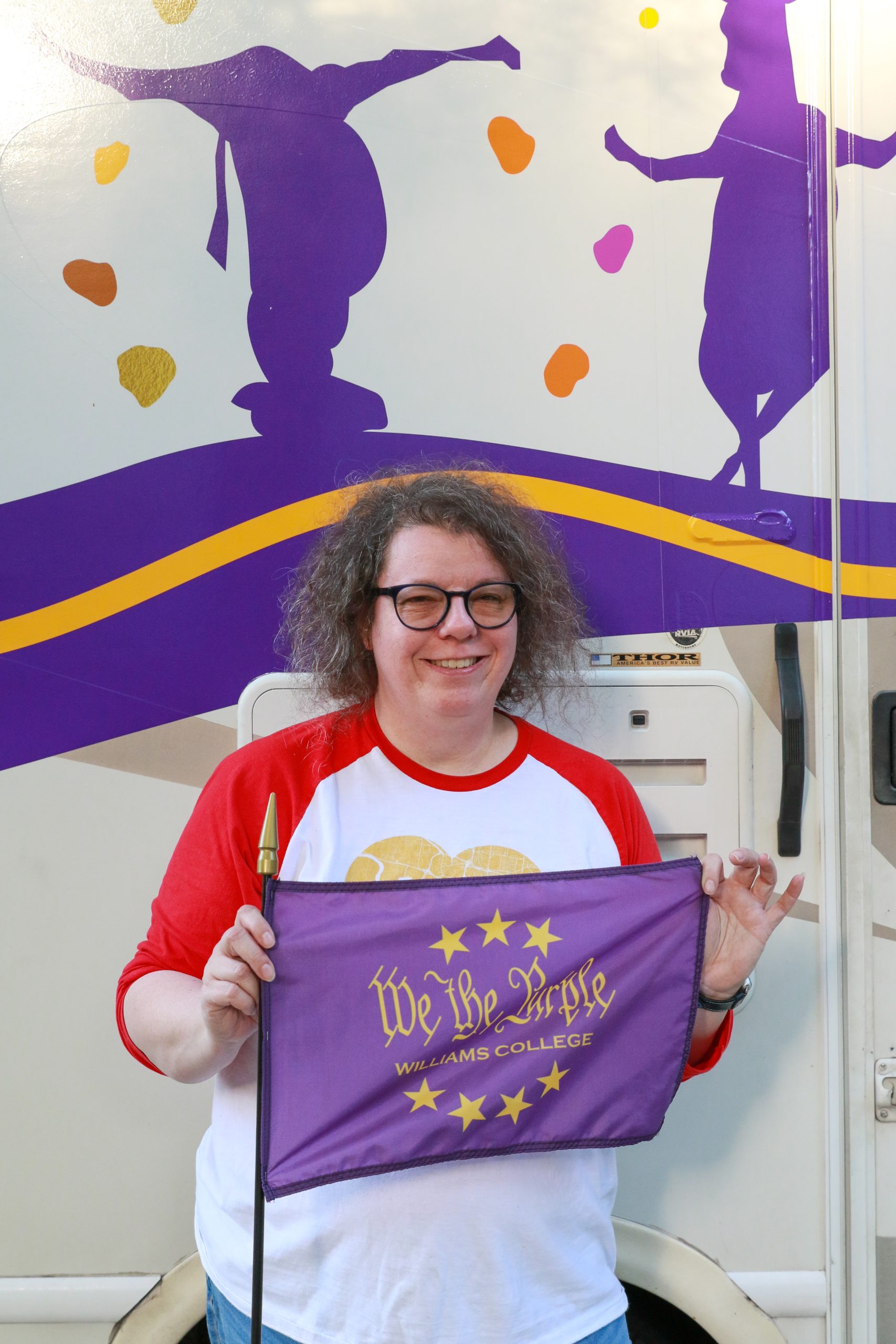 a woman holding a purple flag that says 'We the Purple' with a backdrop of graphics with cows dancing