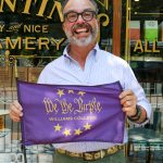 Frank holding a 'We the Purple' flag in front of Clementine's.