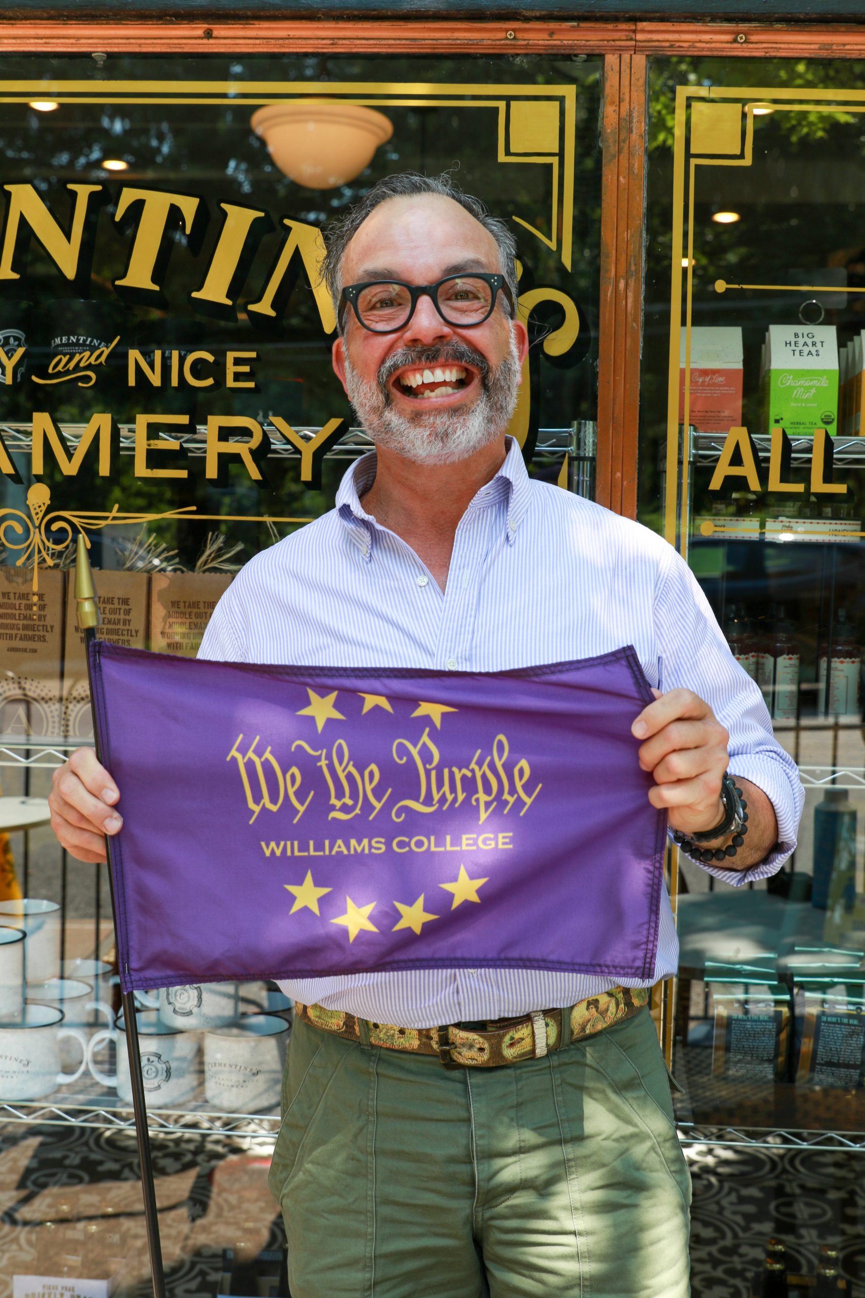 Frank holding a 'We the Purple' flag in front of Clementine's.