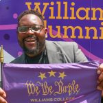 man holding a purple flag with test that reads 'We the Purple'