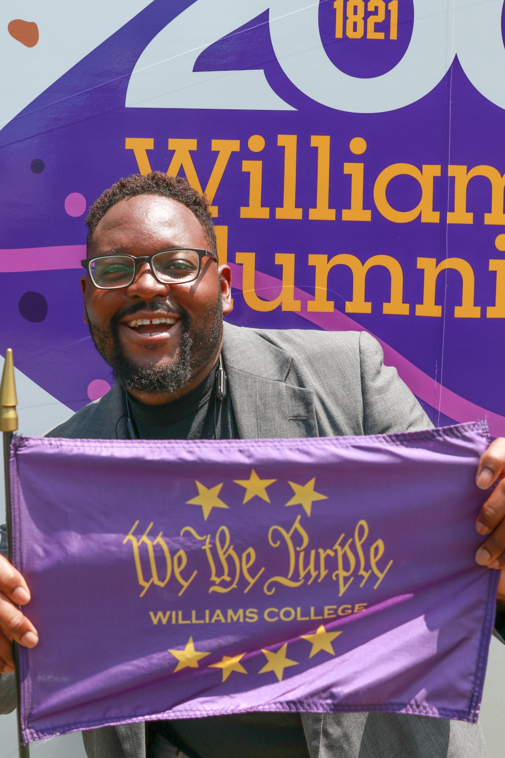 man holding a purple flag with test that reads 'We the Purple'