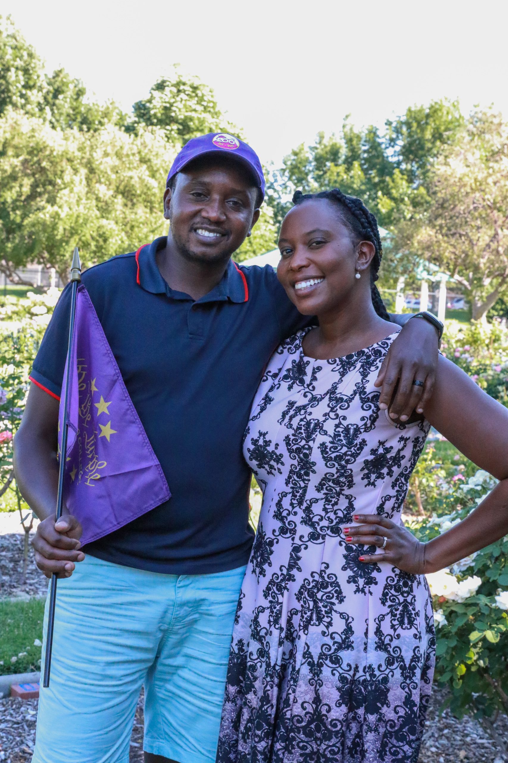 2 people posting or a photo while one holds a purple flag.