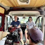 3 people in an on-camera interview inside a van