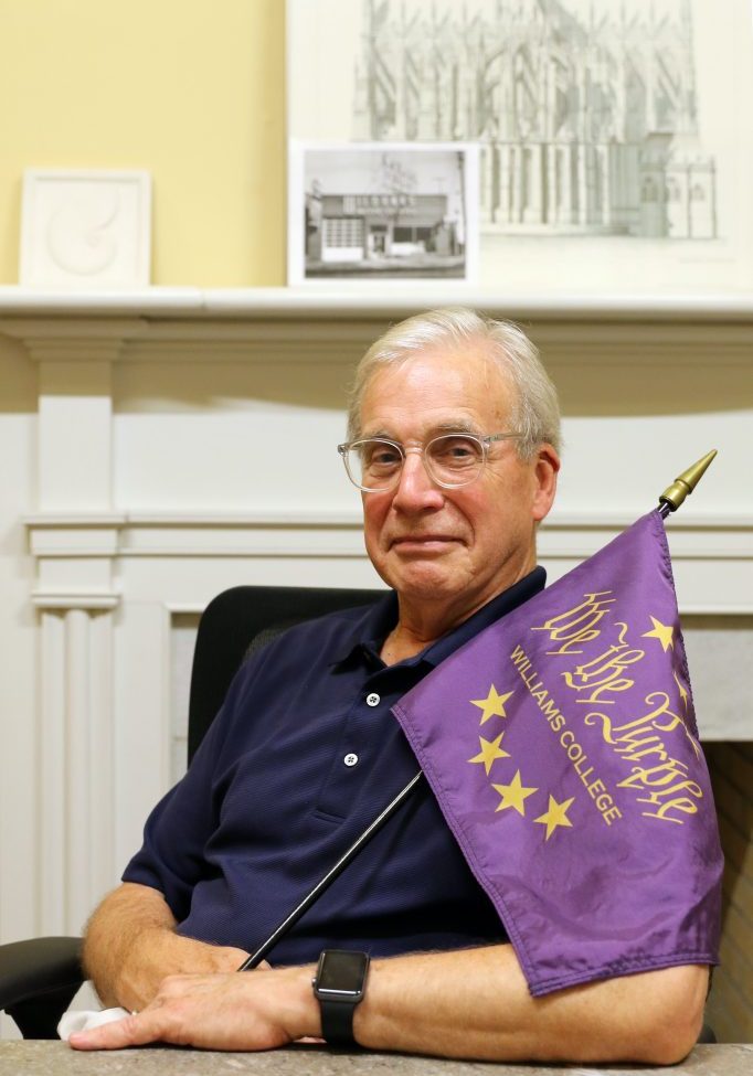 a man holding a purple flag while sitting down