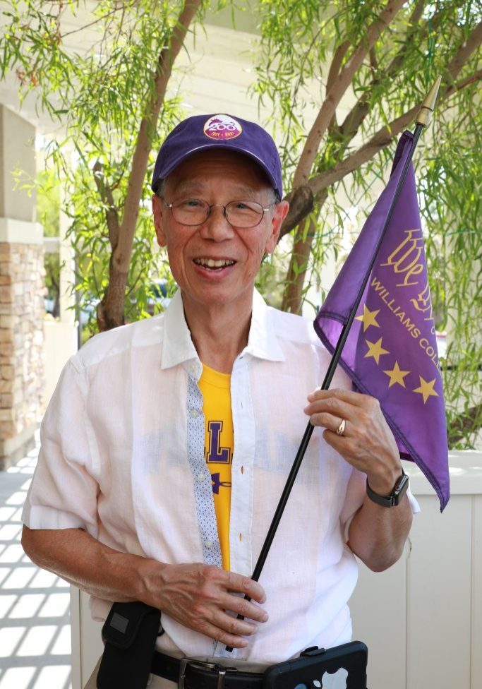 a person wearing a white shirt and a purple baseball cap while holding a purple flag