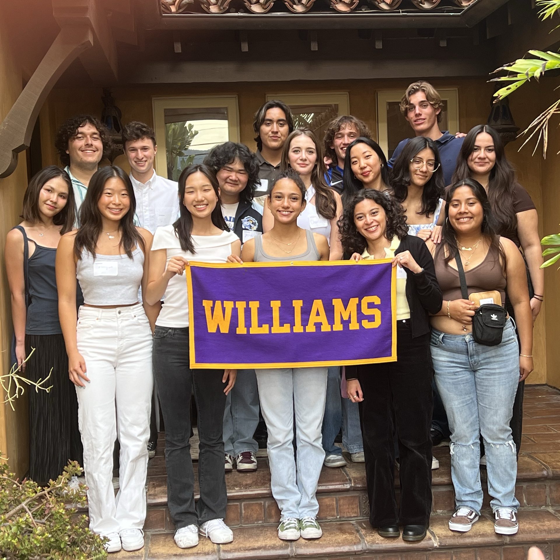 20230819_SummerSendOff-LosAngelesCA_TracyDrozTragos_001 A group of 17 Williams incoming students of the Class of 2027 posing together holding a Williams banner.